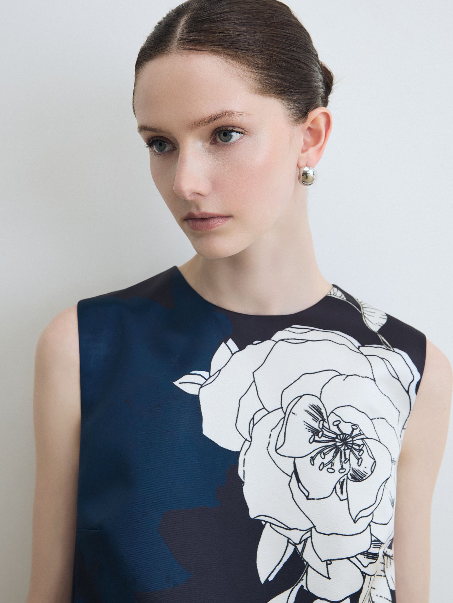 Woman wearing a navy blue dress with white floral design against a plain background