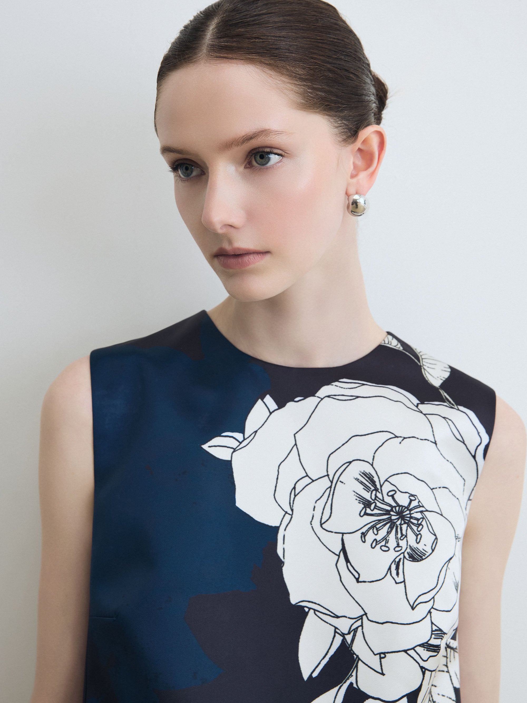 Woman wearing a navy blue dress with white floral design against a plain background