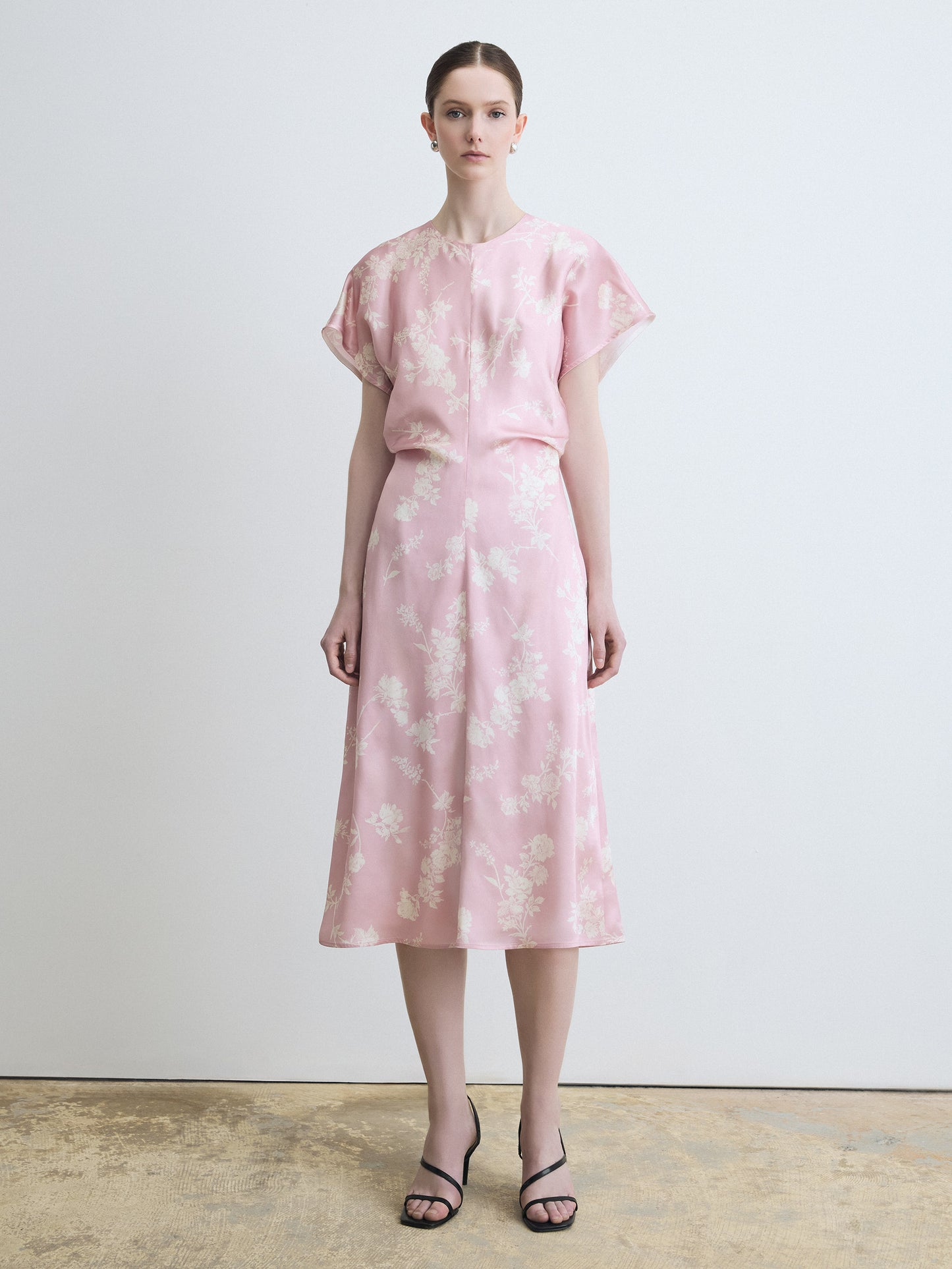 Woman wearing a pink floral dress against a plain background