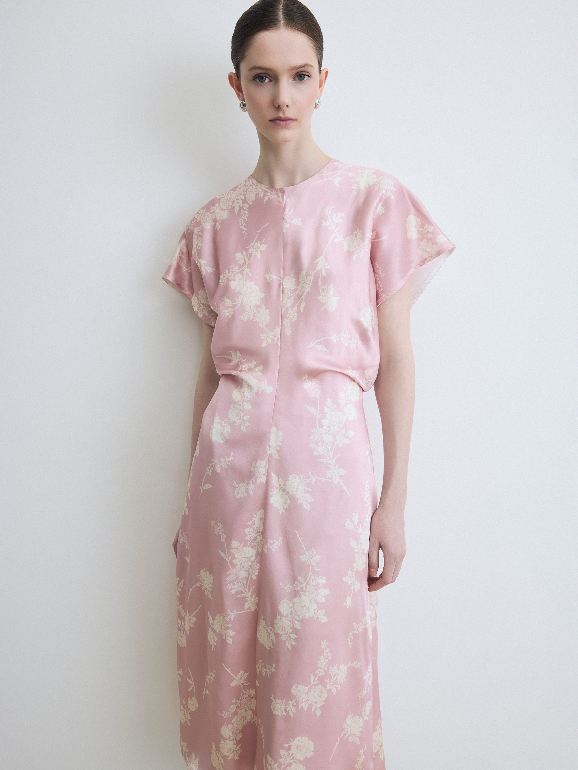 Woman wearing a pink floral dress against a white background
