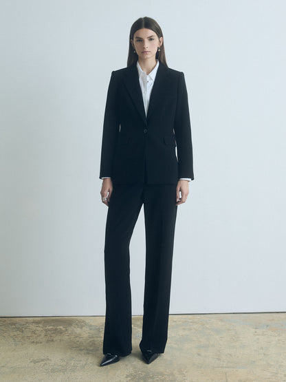 Model wearing a black judith and charles with a white shirt against a plain background