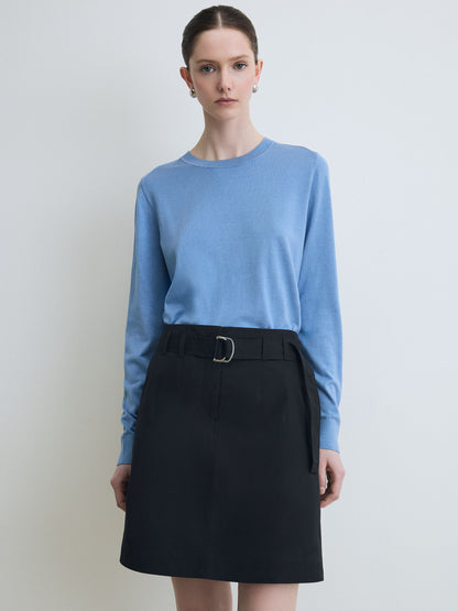 Woman wearing a light blue sweater and black skirt on a plain background
