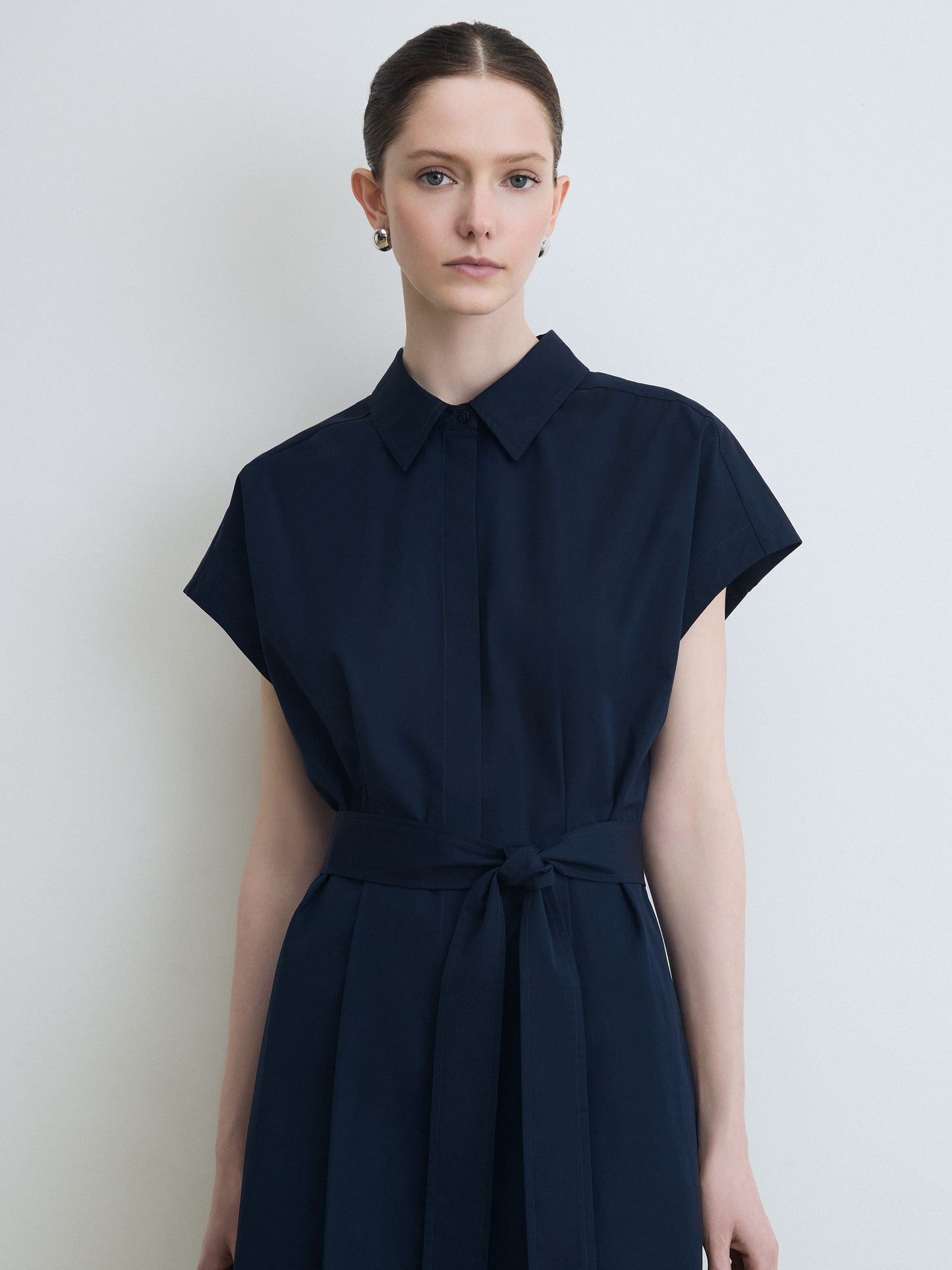 Woman wearing a navy blue dress against a white background