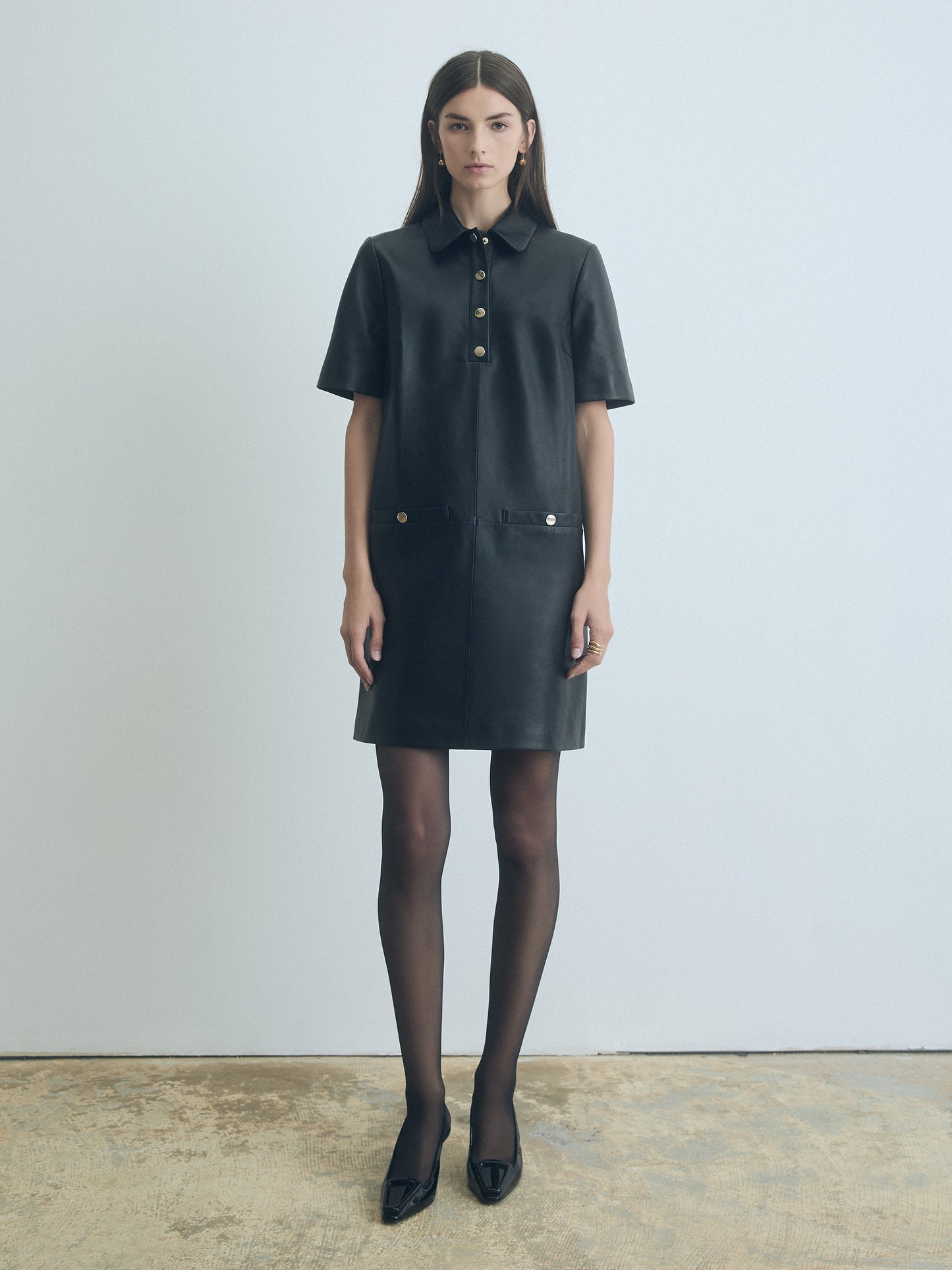 Model wearing Judith and Charles Black leather short sleeve polo dress with spread collar and welt pockets 