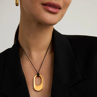 Gold necklace with a pendant worn by a person against a neutral background