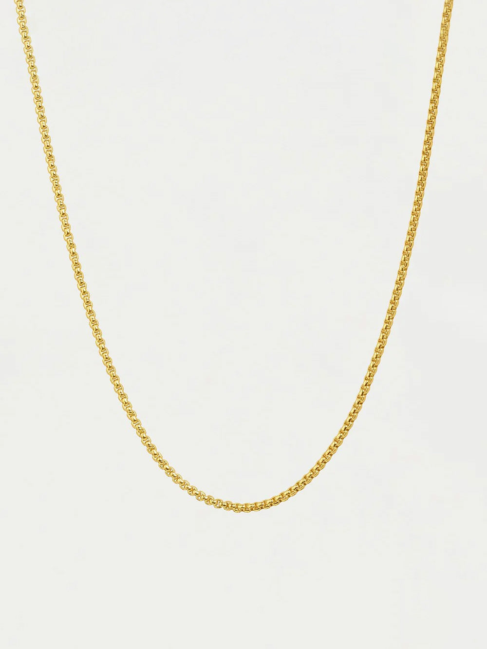 Gold chain necklace on a light beige background