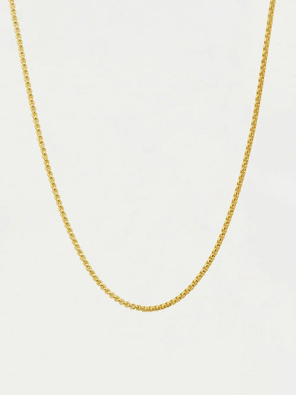 Gold chain necklace on a light beige background