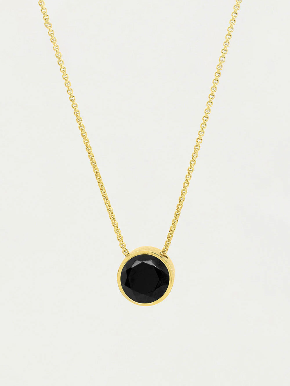 Gold necklace with a black gemstone pendant on a light gray background