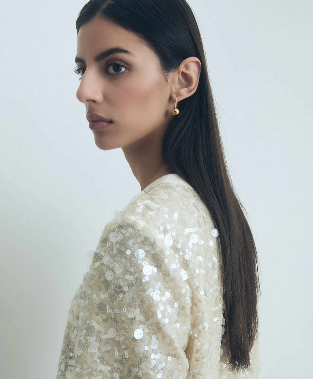 Woman wearing a sparkly white top against a plain background