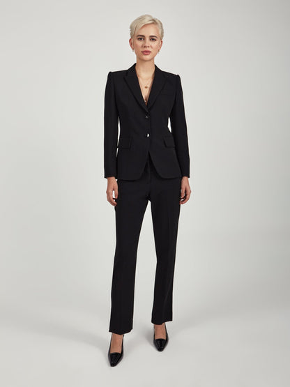 Model wearing slim ankle‑length triacetate trousers in black  tone, featuring a mid‑rise clean waist, slash pockets, back welt pockets, and a tailored slim leg. Styled with a matching blue blazer and black pointed‑toe heels against a minimal light grey background