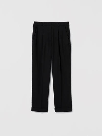Flat‑lay of black pleated cuffed trousers with a clean tailored waistband, slash pockets, and back welt pockets