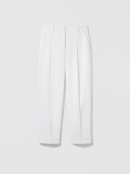 Flat‑lay of off‑white pleated cuffed trousers with slash pockets, welt pockets, and a clean tailored waistband.