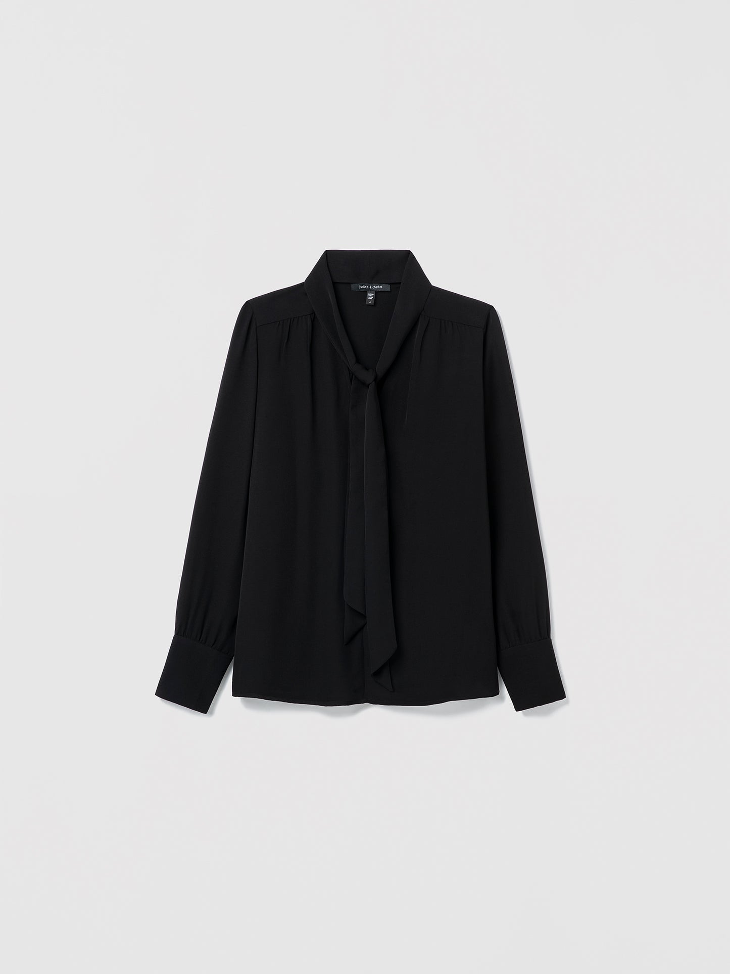 Black blouse with a tie neckline on a light gray background